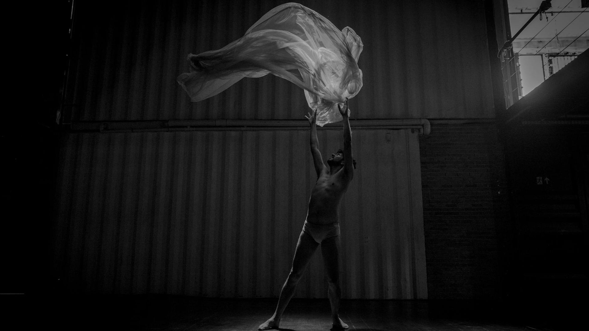 Person in a dynamic, fluid motion pose in a minimalist space.